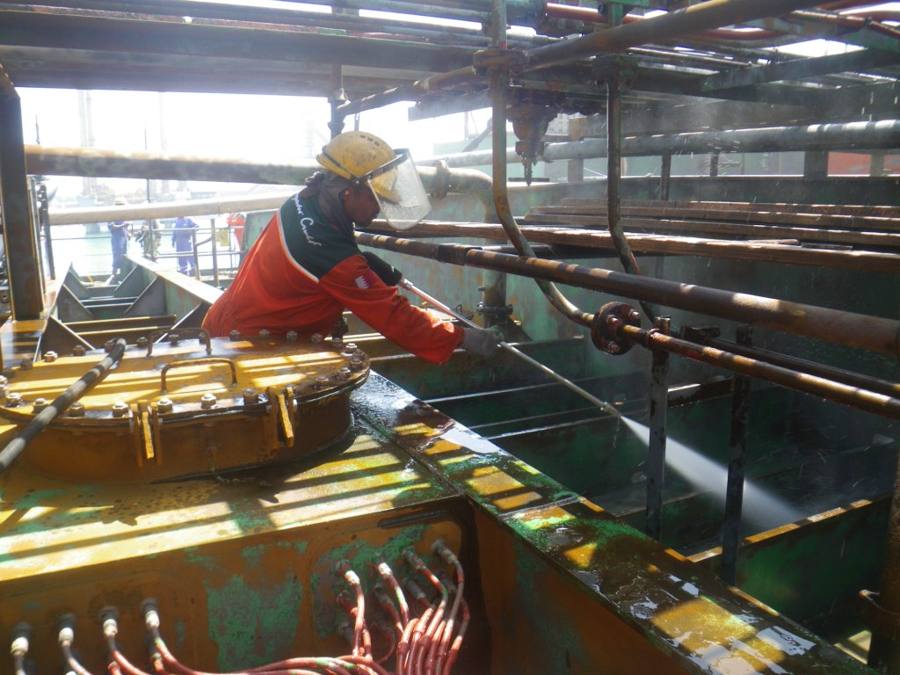 Crew member working on deck pipework at sea
