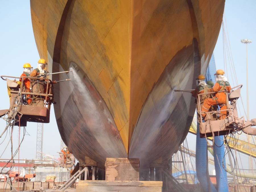 Two crews in man-baskets blasting a ship's bow